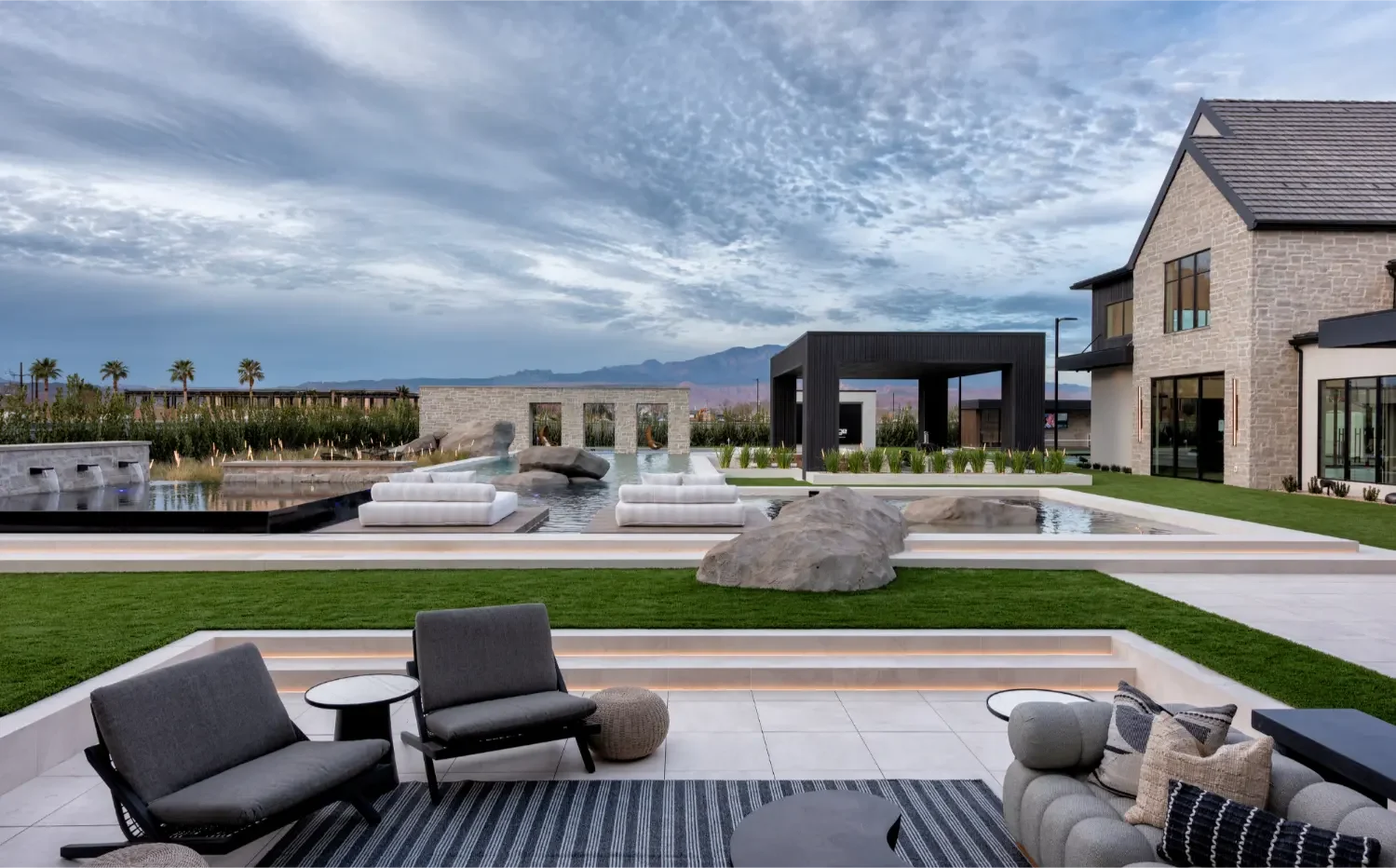Wide view of a Utah backyard pool with floating daybeds, jumping rocks, shallow areas, and mountain views