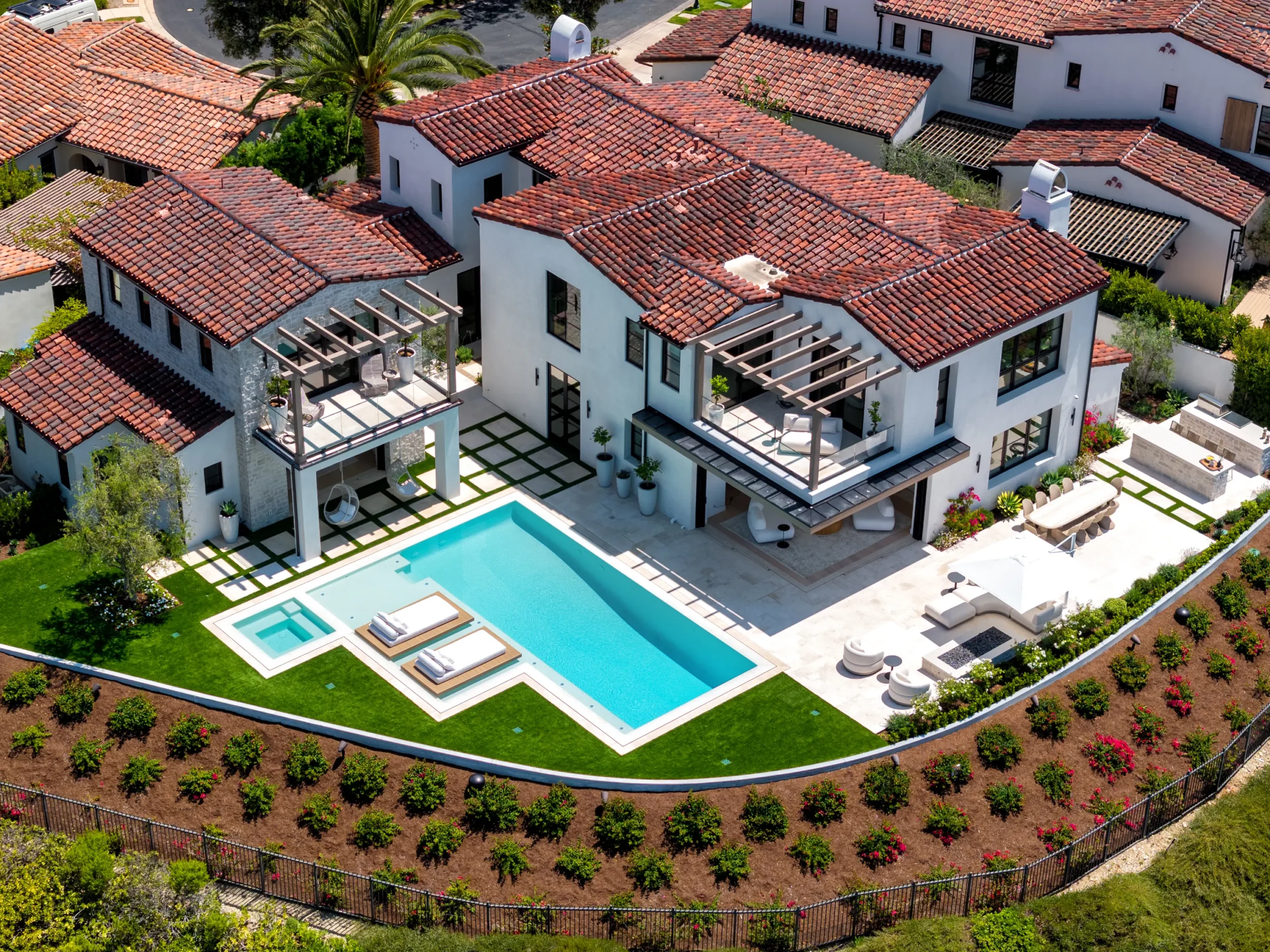 Aerial view of a southern California backyard with pool, spa, in-water daybeds, lawn, dining, and lounge areas