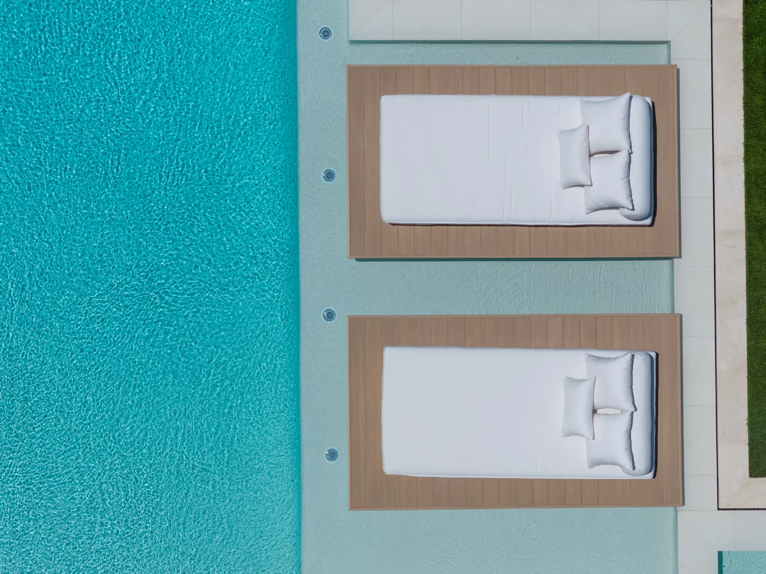 Overhead view of two white daybeds in the pool