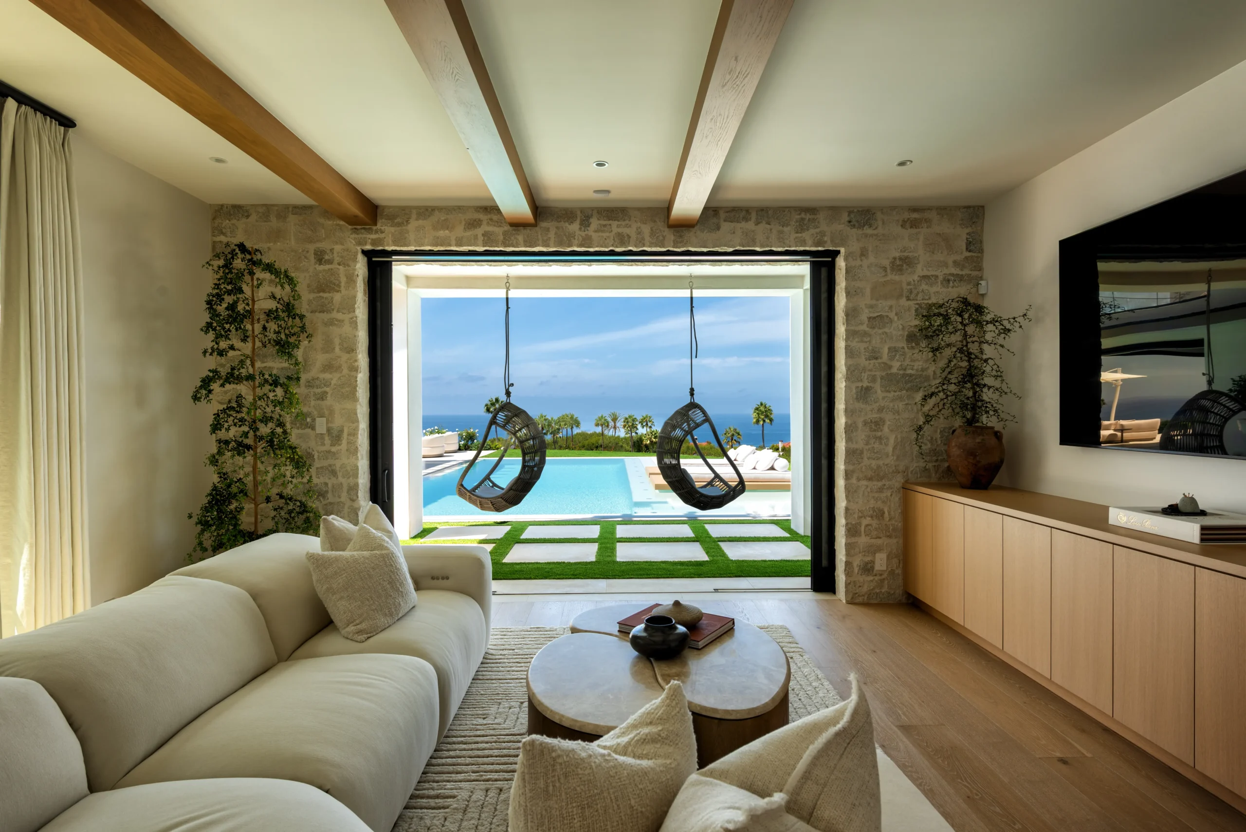 Indoor lounge with a view to hanging chairs and pool with a Pacific Ocean view