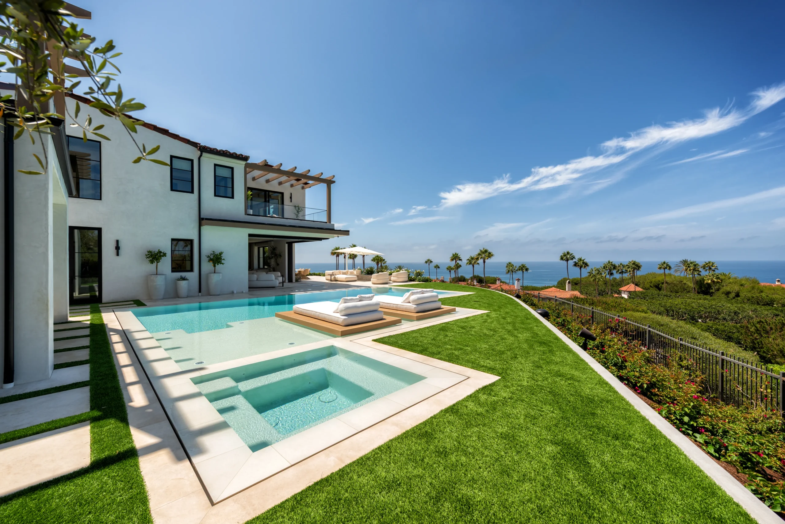 Pool with two floating daybeds facing the home and a covered outdoor lounge