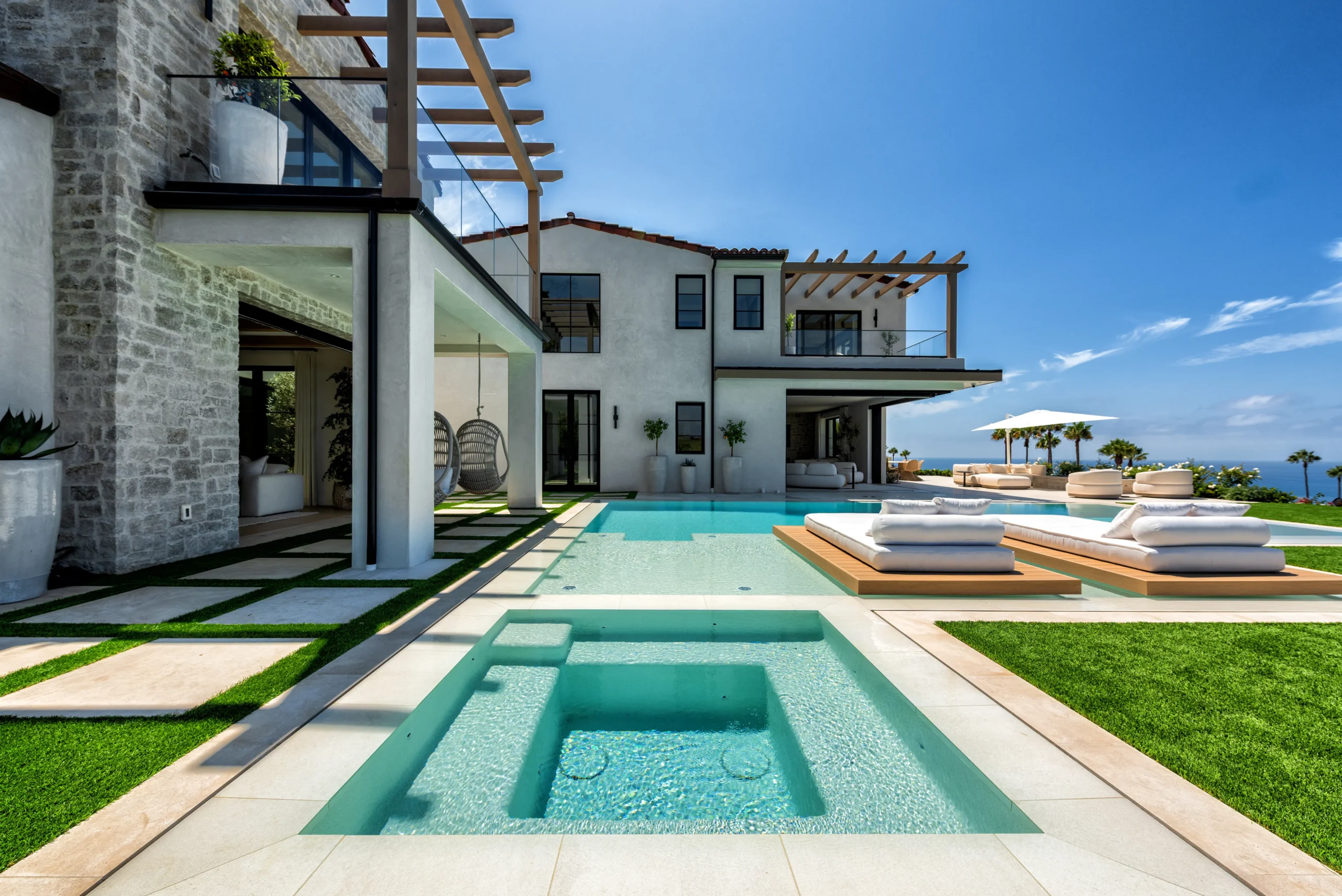 View of resort-inspired yard with zero-edge spa, pool, and multiple seating areas